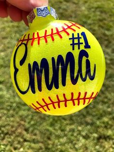 a hand holding up a yellow ornament with the word emma on it