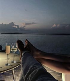 two people sitting at a table with wine glasses on it and one person laying down