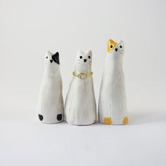 three white cats with black and gold collars are standing in front of each other