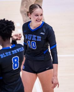 two girls are playing volleyball on the court and one girl is smiling at the other