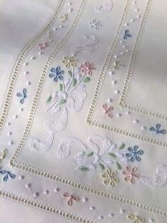 an embroidered tablecloth with flowers and vines on it's edges is shown in close up