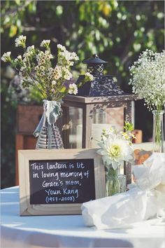 a table topped with vases filled with flowers next to a chalkboard sign that says, this wedding is in loving memory of grace