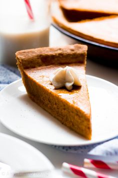 a slice of pumpkin pie on a white plate with a glass of milk in the background