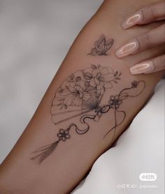 a woman's arm with flowers on it and butterflies flying around the wrist tattoo