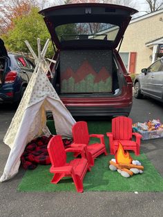 a tent and chairs are set up in front of a car with the back door open