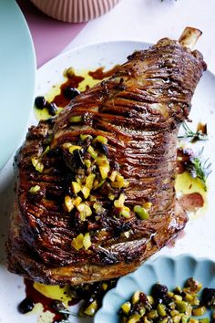 a large piece of meat sitting on top of a white plate next to other food