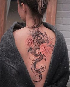 the back of a woman's neck with flowers and a snake tattoo on it