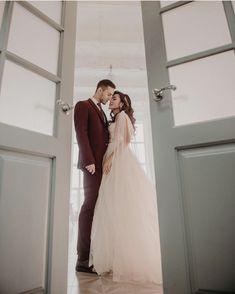 a bride and groom standing in an open doorway