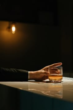 a man in a suit is holding his hand out to a glass on a table