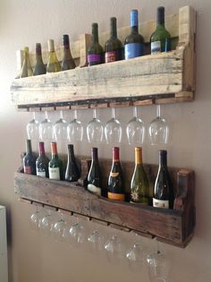 wine glasses and bottles are lined up on a wooden shelf in front of a wall mounted wine glass rack