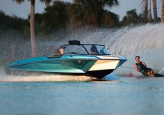 two people on water skis being pulled by a speedboat in the water near palm trees