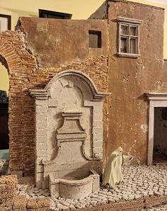 a statue of a fountain in the middle of a room with brick walls and doorways