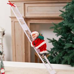 a santa clause doll climbing up a ladder next to a christmas tree