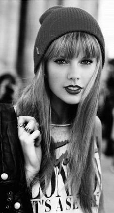 black and white photograph of a woman with long hair wearing a beanie, holding a handbag