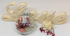 a glass ornament with the word love written on it next to some flowers