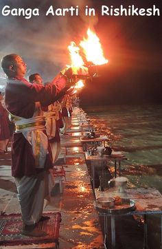 men in traditional garb holding fire torches on the water's edge with text overlay that reads, ganga arti in rishikesh