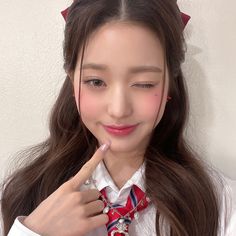 a girl with long brown hair wearing a red and white striped tie holding a pencil in her right hand