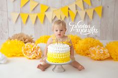 a baby sitting on the floor in front of a cake with yellow ruffles