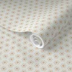 a white and gold wallpaper with small flowers on the side, next to a roll of paper