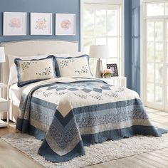 a bedroom with blue walls, white furniture and a quilted bedspread on the bed