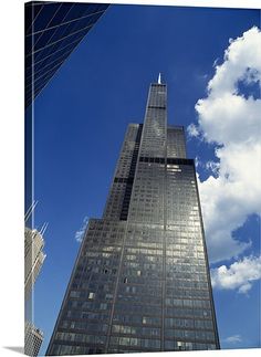 an upward view of a skyscraper with clouds in the background