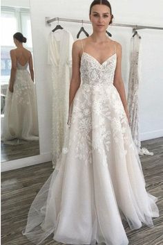 a woman standing in front of a mirror wearing a wedding dress