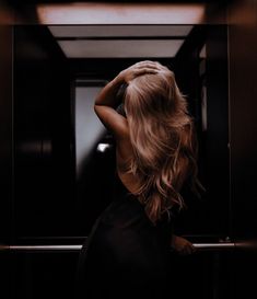 a woman standing in front of a mirror with her hands on her head