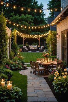 an outdoor dining area with lights strung over the table and chairs, surrounded by greenery