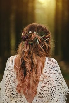 the back of a woman's head with long hair and flowers in her hair