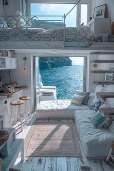 a living room filled with furniture next to a window overlooking the ocean and cliffs in the distance