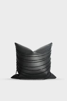 a black leather pillow sitting on top of a white surface