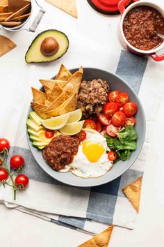 an image of a plate of food with chips and tomatoes on the side, avocado