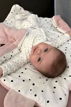 a baby laying on top of a bed with pink sheets and polka dot blankets around it