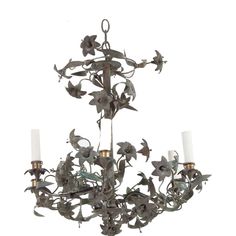 an iron chandelier with flowers and candles on the bottom, against a white background