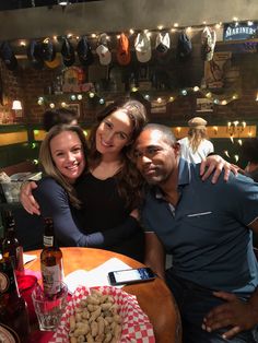 two women and a man sitting at a table in a restaurant with food on it