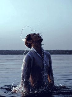 a dog is splashing water on its head in the water while standing in the ocean