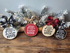 three decorated cookies are sitting on top of a wooden table next to evergreen branches and pine cones