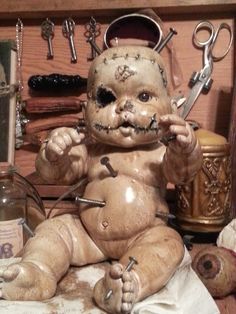 a creepy looking doll sitting on top of a table next to scissors and other items