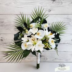 a bouquet of white flowers and greenery on a table