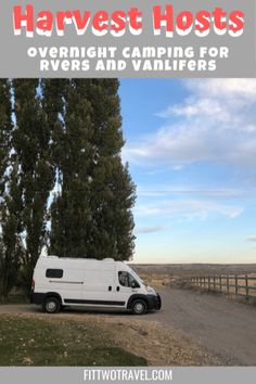 a white van parked on the side of a road next to a fence and trees