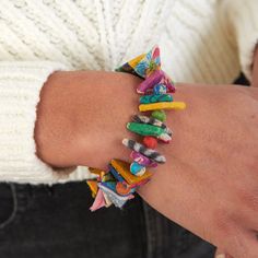 a close up of a person's arm wearing a bracelet with colorful objects on it