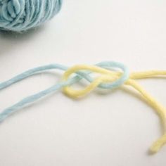 two skeins of yarn sitting next to each other on a white surface with blue and yellow crochet