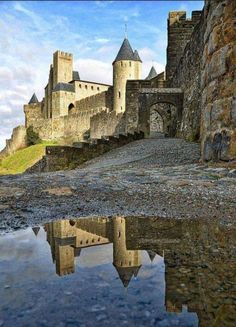 an old castle with water in the foreground and its reflection on the ground below