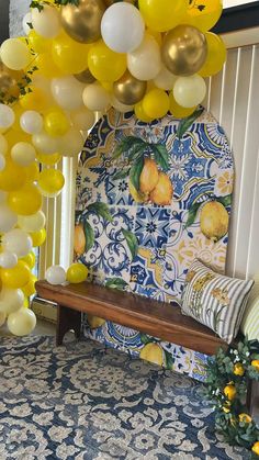 yellow and white balloons hang from the ceiling above a bench in front of a patterned wall