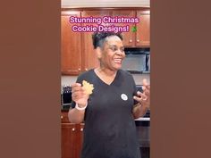 the woman is holding up some cookies in her hand and smiling at the camera while wearing a black t - shirt that says, stuking christmas cookie designs