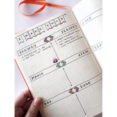 a hand holding an open planner book with arrows on the page and ribbon around it