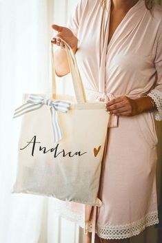 a woman holding a personalized shopping bag with a bow on the handle and name