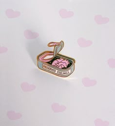 a pink and black pin with the words preserved feelings on it's back side