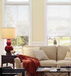 a living room filled with furniture and two windows covered in shades of white shutters