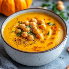 a white bowl filled with soup and garnished with chickpeas